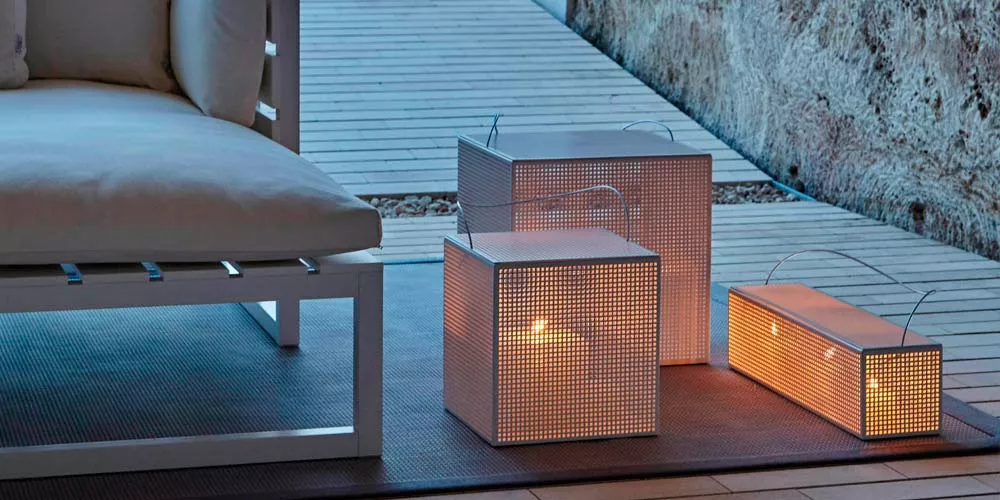 Gandia Blasco Fez Laternen in Weiß auf einer Holzterrasse bei Dämmerung, stimmungsvolle Beleuchtung neben einem weißen Sofa.