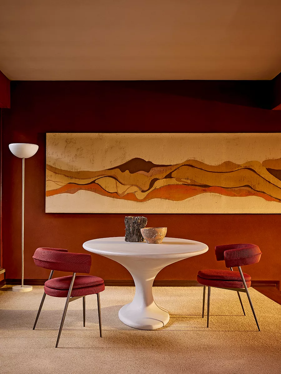 Zanotta Tavolo Fenice in einem stilvollen Wohnzimmer mit rotem Teppich zwei roten Stühlen und einer Stehlampe im Hintergrund