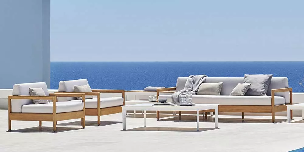 Varaschin Bali Loungegruppe in Weiß und Holzoptik auf einer Terrasse mit Meerblick, ideal für stilvolle Gartenmöbel-Arrangements.