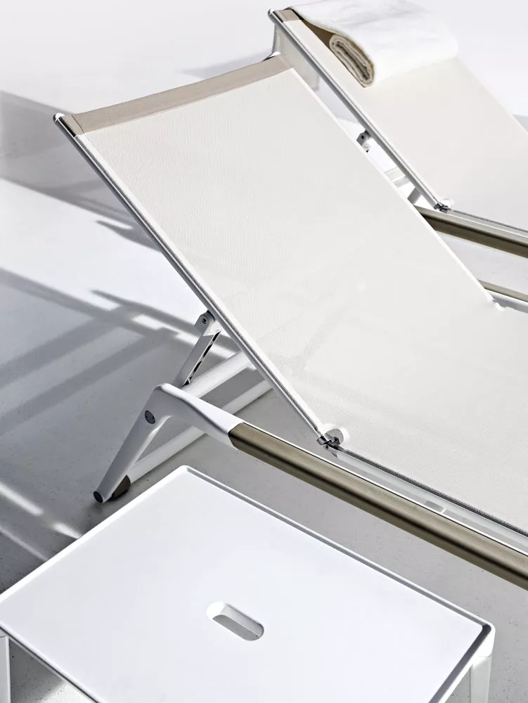 B&B Italia Mirto Outdoor Sonnenliege in weiß mit Handtuch auf der Lehne und einem weißen Beistelltisch im Vordergrund Moodbild im Freien