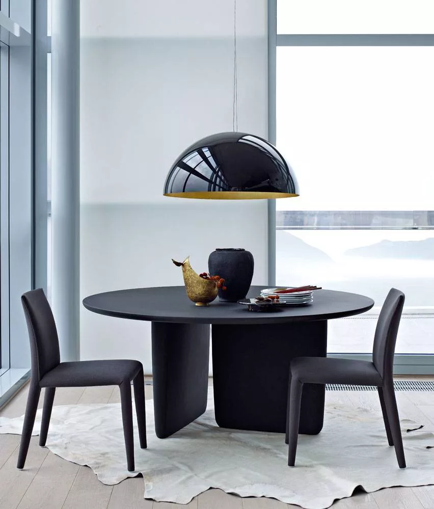 B&B Italia Tobi Ishi Tisch in einem modernen Esszimmer mit zwei Stühlen und einer schwarzen Hängelampe auf einem hellen Teppich.