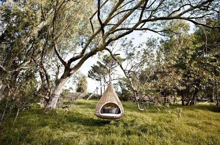 Nestrest Hanging Lounger rund 200 cm von Dedon hängt an einem Baum in einer grünen Wiese umgeben von Bäumen und Natur