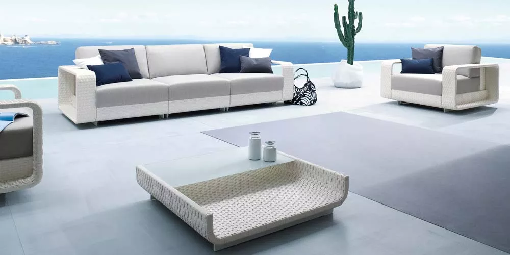 Roberti Hamptons Outdoor Loungegruppe in Weiß auf einer Terrasse mit Meerblick, bestehend aus Sofa, Sessel und Couchtisch.