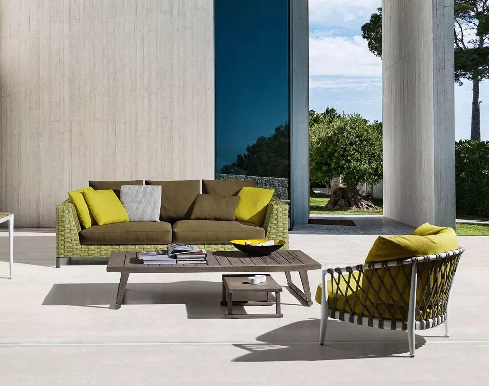 B&B Italia Erica Loungegruppe mit grünem Sofa und gelben Kissen auf einer Terrasse mit Blick auf Garten und Himmel.