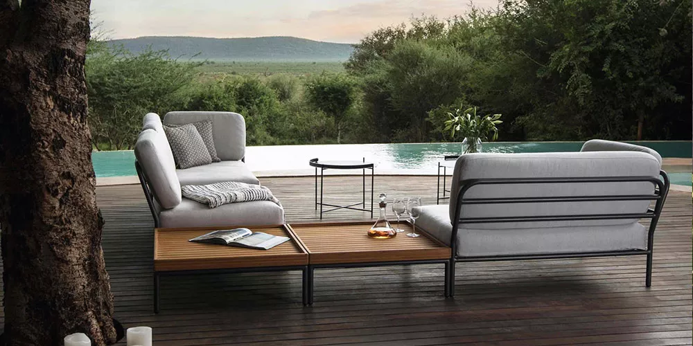 Gartenmöbel-Set von Houe, Kollektion Level, in Grau auf Holzterrasse mit Blick auf Pool und Landschaft, stimmungsvolle Abenddämmerung.