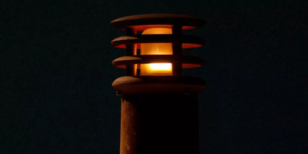 Royal Botania Rusty Gartenleuchte in Rostoptik, leuchtend in der Dunkelheit, vor schwarzem Hintergrund, stimmungsvolles Bild.