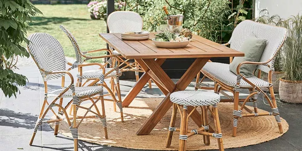 Sika-Design Affäire Essgruppe in Natur und Weiß auf einer Terrasse mit grünem Garten im Hintergrund, bestehend aus Tisch, Stühlen und Hocker.