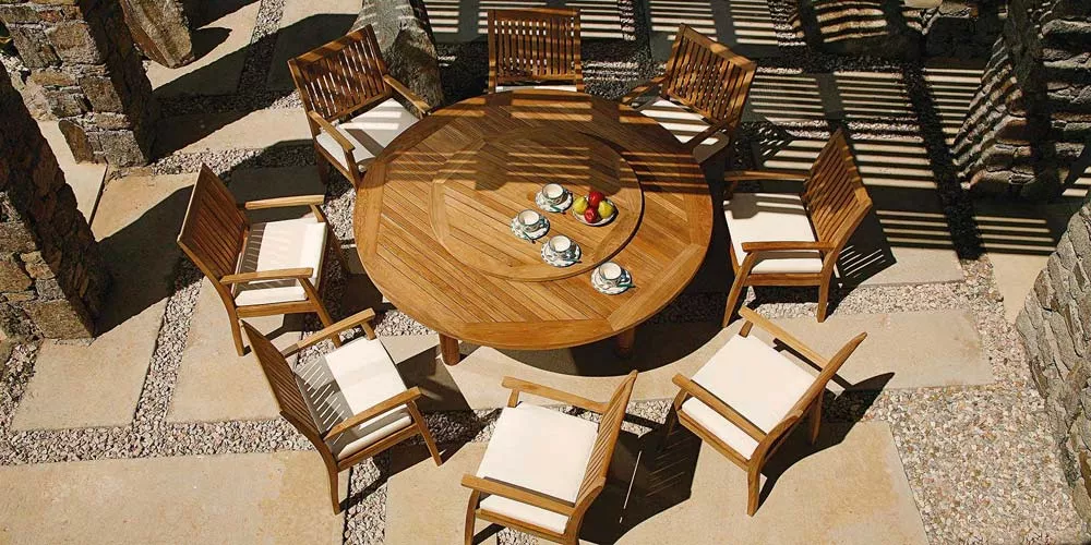 Barlow Tyrie Drummond Essgruppe aus Teakholz, runder Tisch mit acht Stühlen, Vogelperspektive, auf Steinboden im Freien.