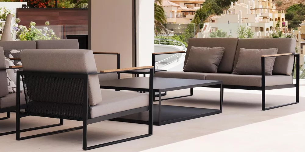 Roshults Kollektion Garden Easy Lounge in Grau auf einer Terrasse mit modernem Hintergrund, bestehend aus Sofa und Sesseln.