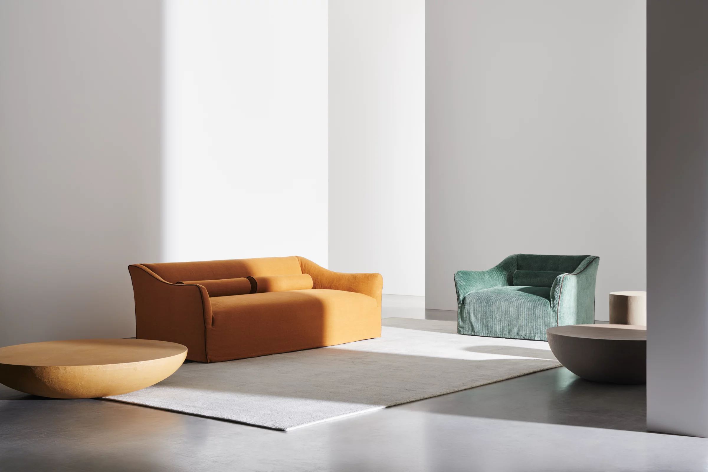 Gervasoni Ghost Sofa in Orange und Sessel in Grün in einem modernen Wohnzimmer mit minimalistischer Einrichtung und natürlichem Licht.