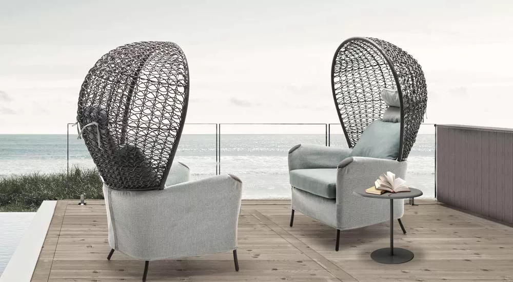 Kenneth Cobonpue Dolly Loungegruppe in Grau auf einer Terrasse mit Meerblick, bestehend aus zwei Sesseln und einem kleinen runden Tisch.