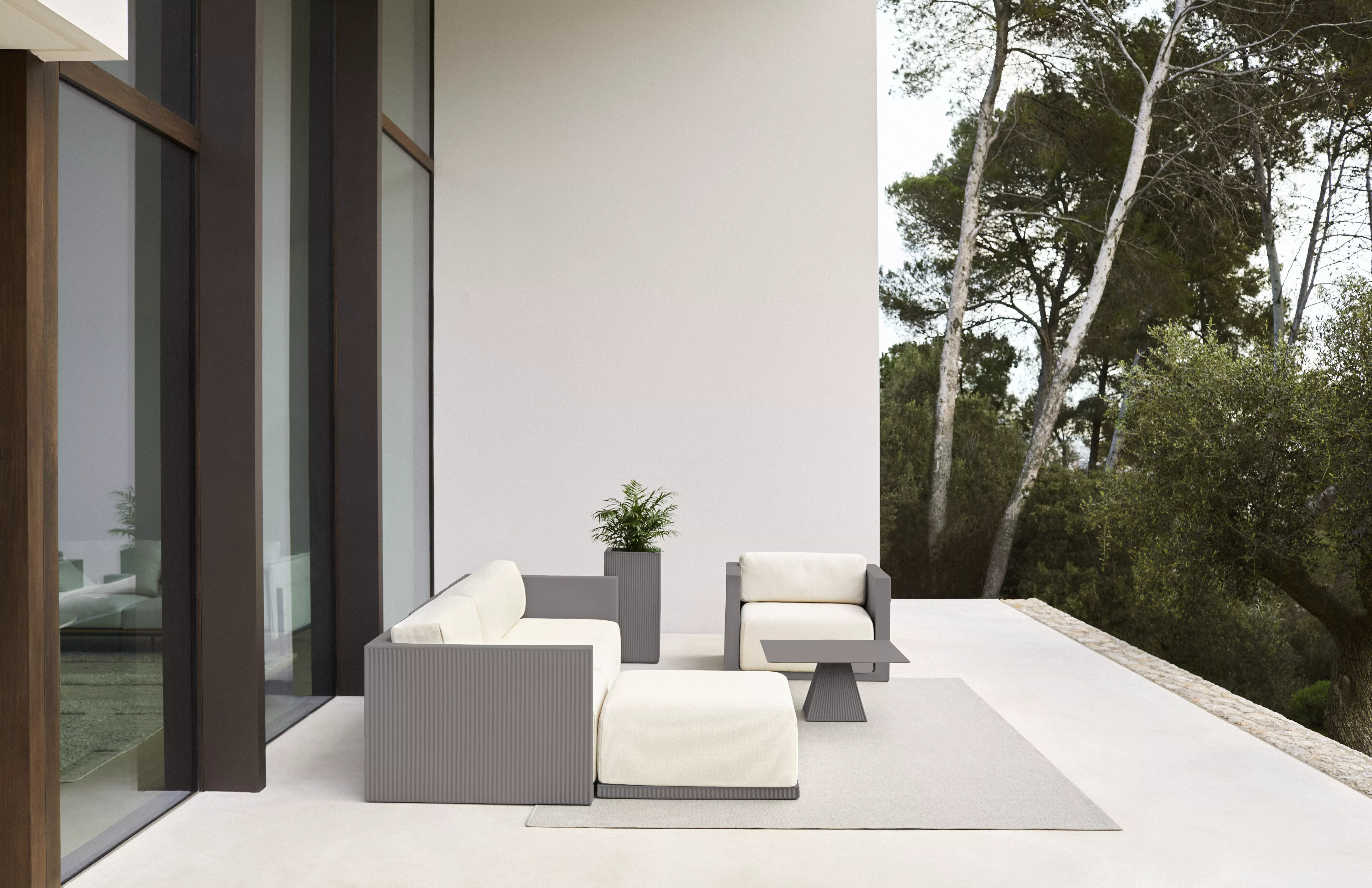 Vondom Gatsby Sofa von Ramon Esteve in Weiß auf einer Terrasse mit Meerblick, moderne Architektur im Hintergrund.