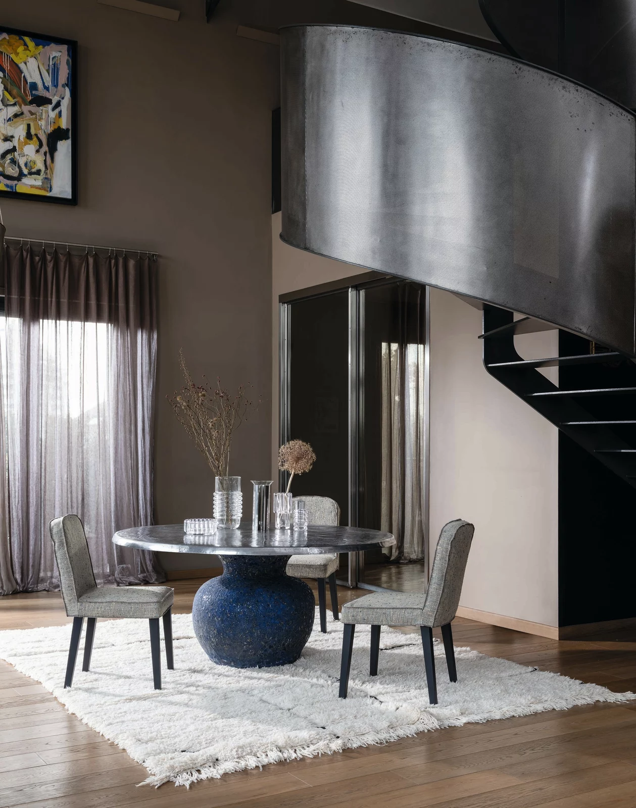 Gervasoni Tisch und Stühle in einem modernen Wohnzimmer mit Teppich und Wendeltreppe im Hintergrund