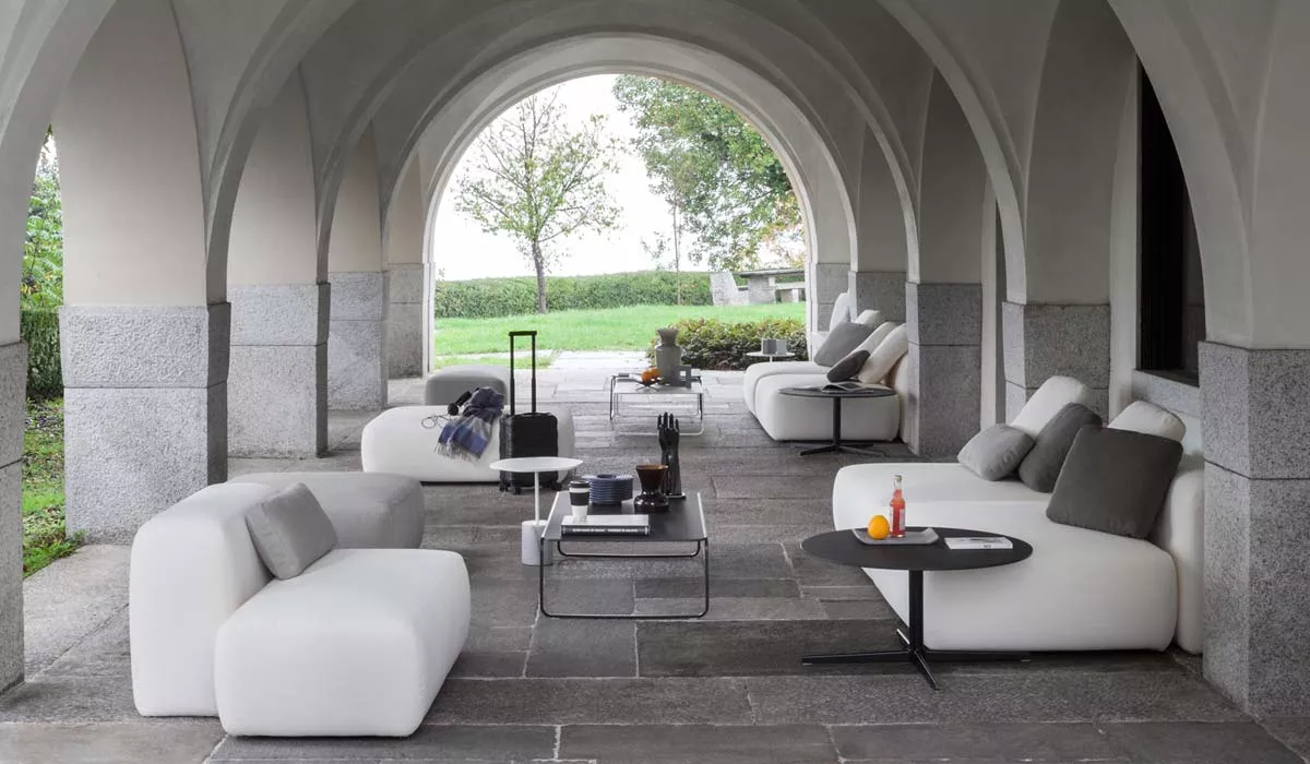 Lapalma PLUS Loungegruppe in Weiß auf einer überdachten Steinterrasse mit Blick auf einen Garten, stimmungsvolles Ambiente.