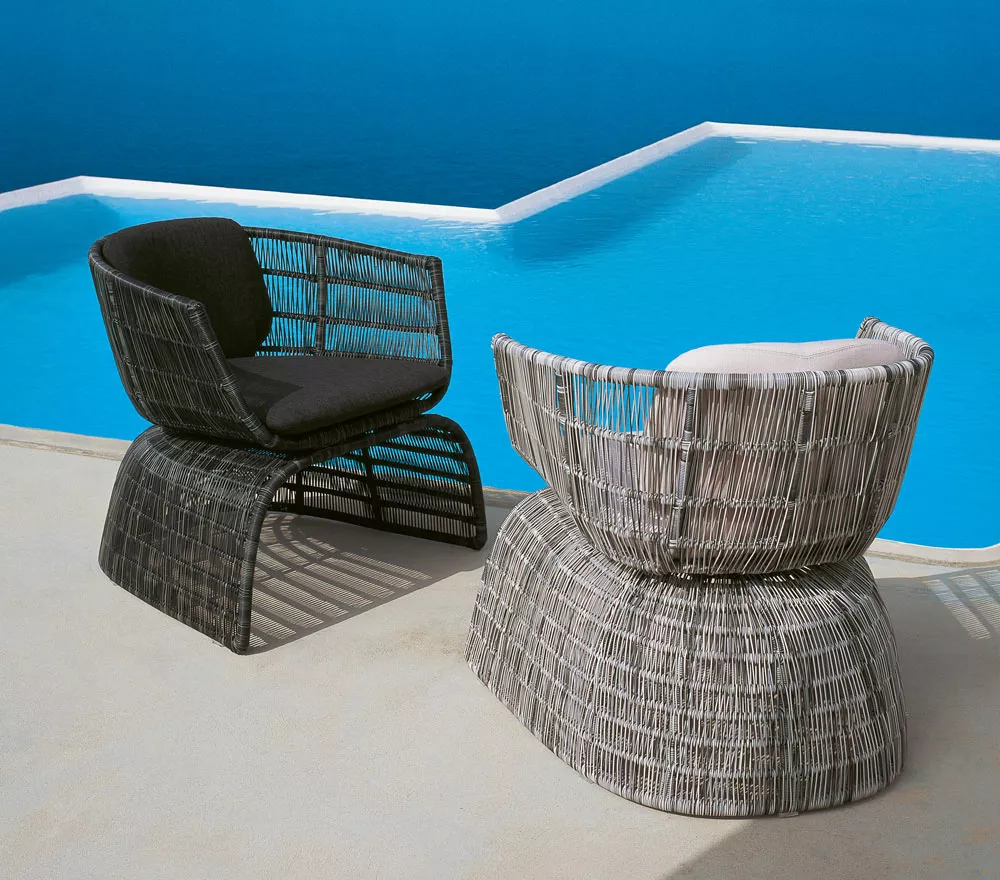 Zwei B&B Italia Crinoline Outdoor Sessel stehen auf einer Terrasse mit Blick auf einen Pool und das Meer im Hintergrund.