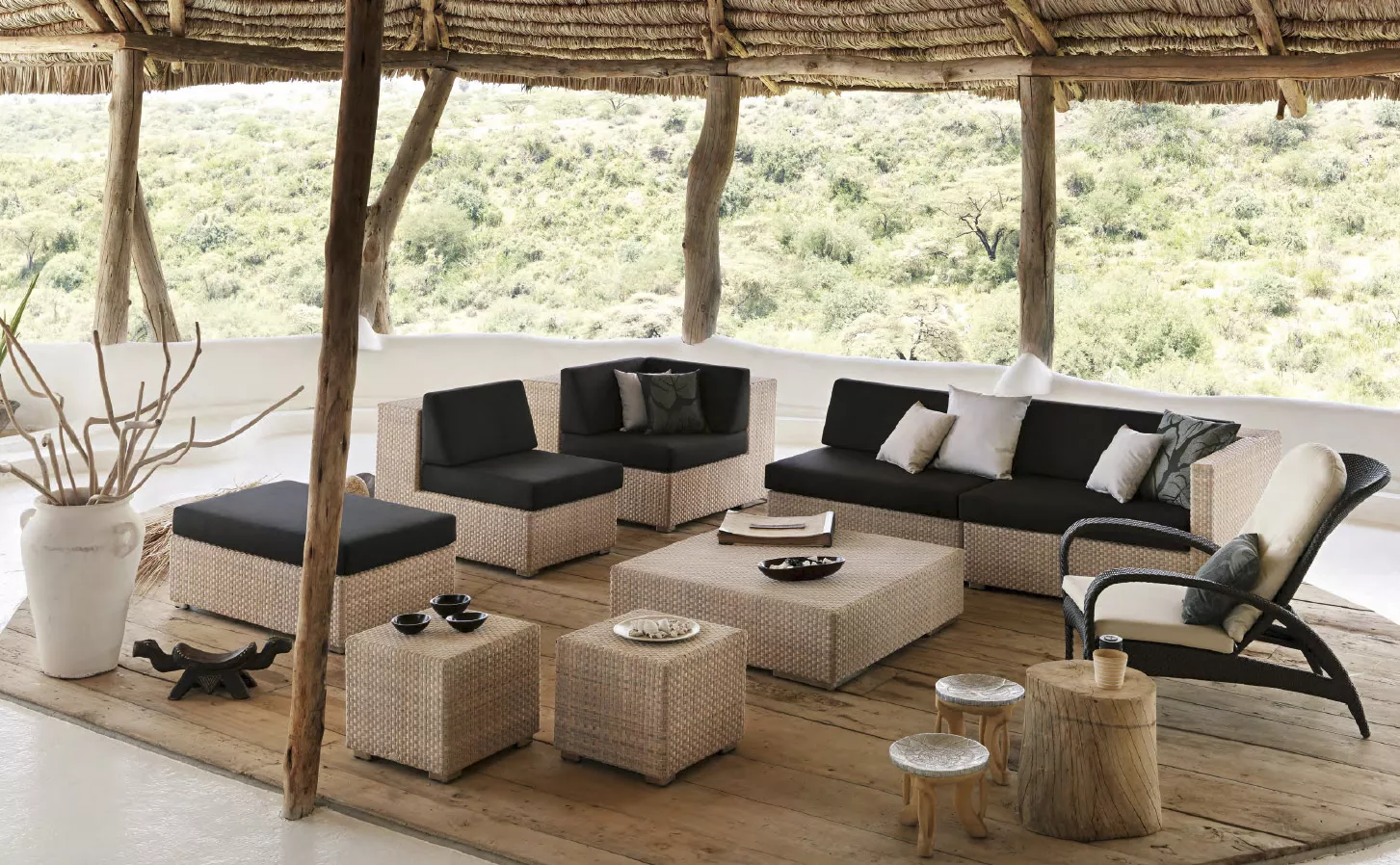 Dedon Lounge hochwertige Gartenmöbel in einer gemütlichen Outdoor-Szene mit Sofas Sesseln und Tischen auf einer überdachten Terrasse mit Blick auf die Natur