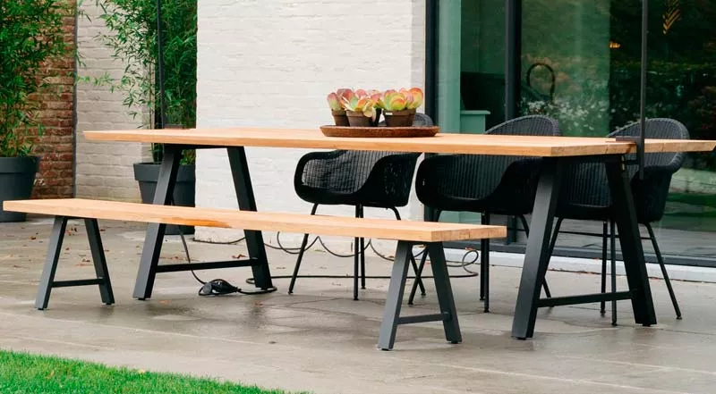 Matteo Gartenmöbel-Set mit schwarzem Gestell und Holztischplatte, bestehend aus Tisch, Bank und Stühlen, auf einer Terrasse.
