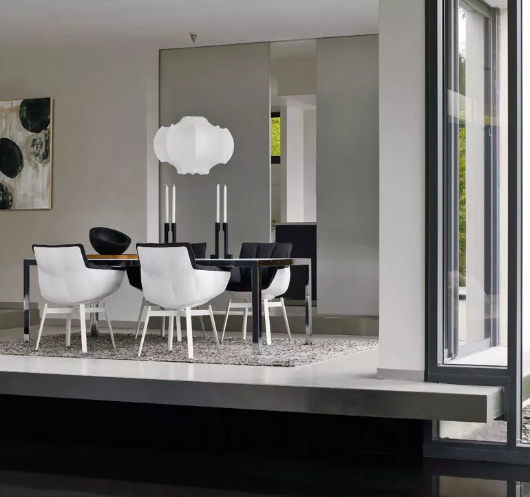 Esszimmer mit B&B Italia Husk Outdoor Armlehnstühlen in Weiß um einen modernen Esstisch mit Kerzenleuchtern und Kunst an der Wand