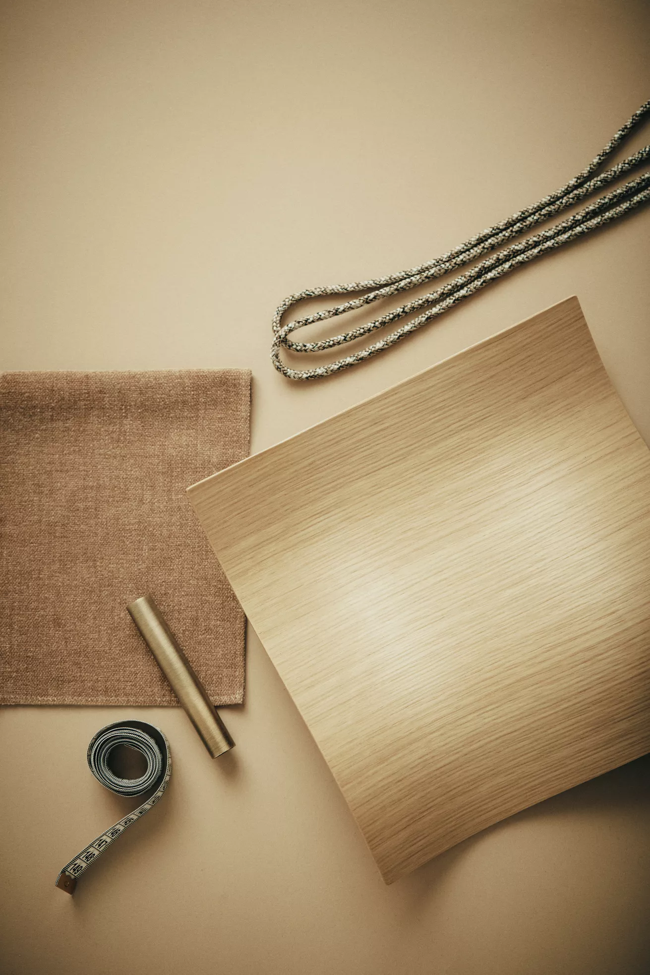 Beige Hintergrund mit Stoffmuster, Holzfurnier, Kordel und Maßband, technische Darstellung für Handwerksprojekt.