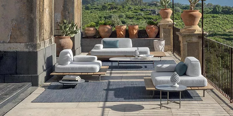 Ethimo Calipso Outdoor-Sofa in Weiß auf einer Terrasse mit Blick auf grüne Landschaft, umgeben von Terrakotta-Pflanzgefäßen.