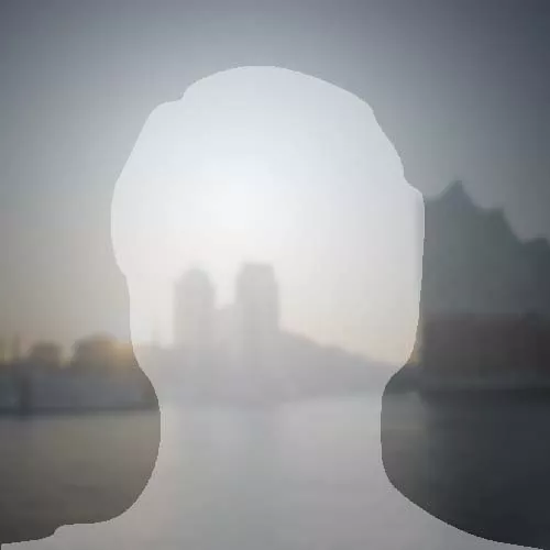 Platzhalterbild mit unscharfem Hintergrund einer Stadtansicht bei Sonnenuntergang, Silhouette im Vordergrund.