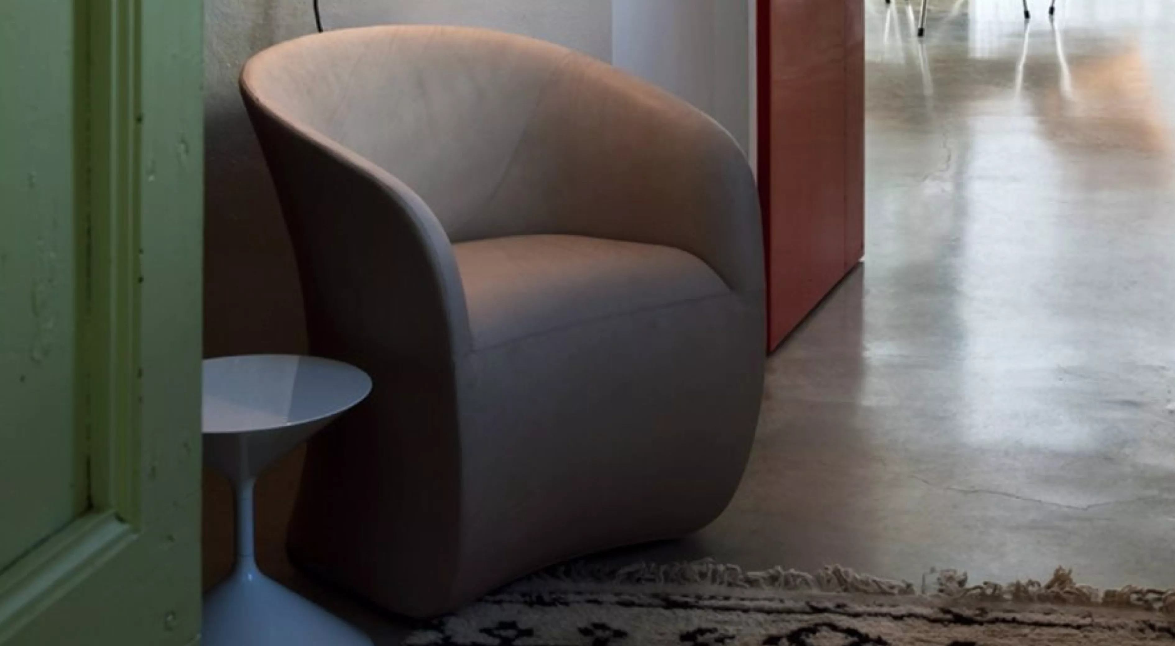 Beiger Calla-Sessel von Villa Schmidt in modernem Raum mit Betonboden und Teppich, seitliche Perspektive.