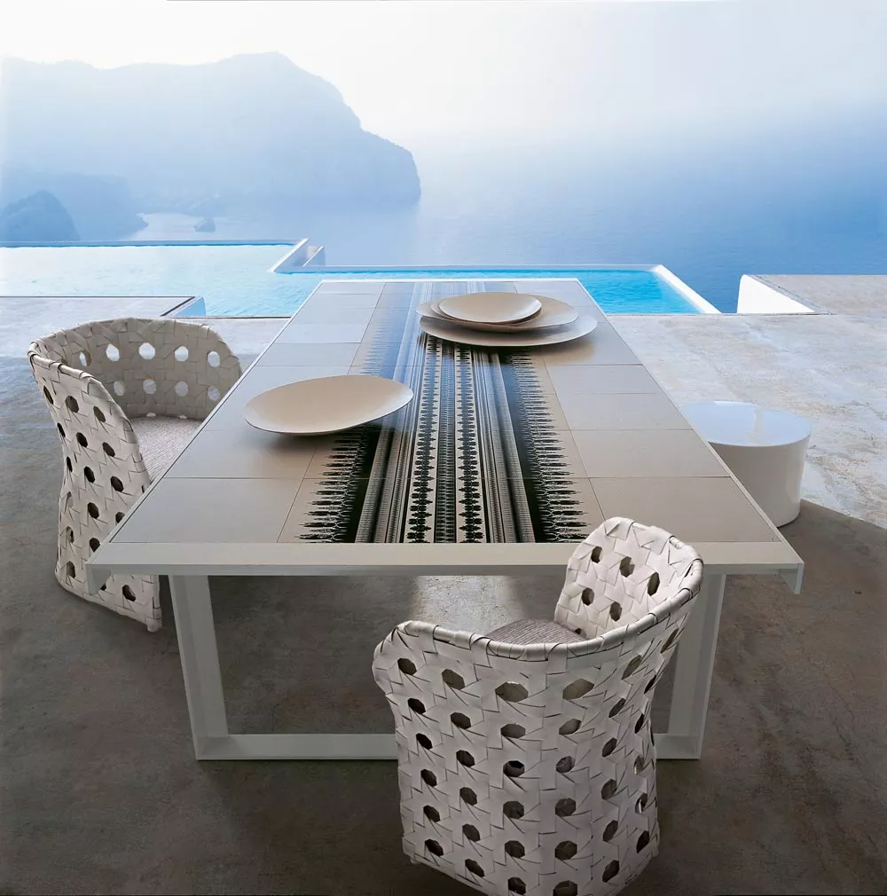 B&B Italia Canasta Outdoor Essgruppe auf einer Terrasse mit Blick auf das Meer und Berge im Hintergrund Mood Bild mit gedecktem Tisch und Stühlen