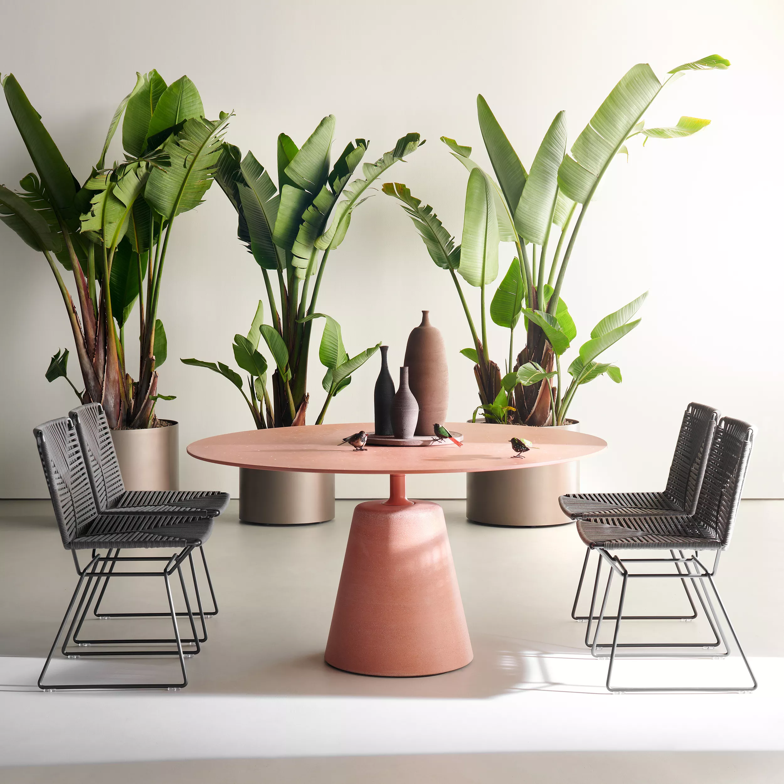 MDF Italia Rock Table in einem Raum mit Pflanzen und vier Stühlen dekoriert mit Vasen und kleinen Figuren auf dem Tisch