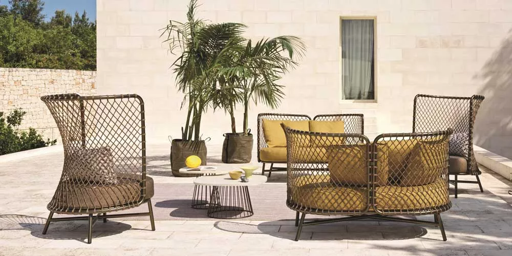 Gartenmöbel-Set Roberti Charme in Braun und Gelb auf einer Terrasse mit Palmen im Hintergrund, stimmungsvolles Outdoor-Setting.