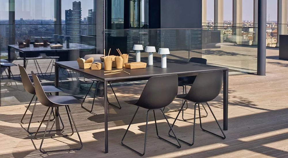 Outdoor-Essgruppe von Lapalma, Modell MIUNN, in Schwarz auf einer modernen Terrasse mit Stadtblick, bestehend aus Tisch und vier Stühlen.