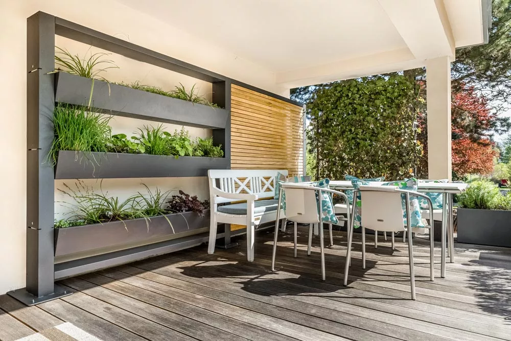Gartensilber Vertikalgarten mit Thermoesche-Sichtschutz, 200x20 cm, auf einer Terrasse mit Holzboden und Gartenmöbeln im Hintergrund.