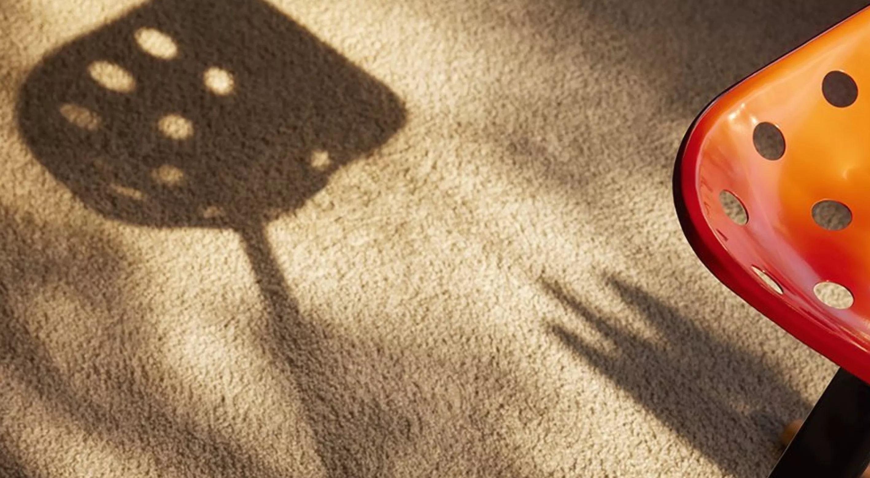 Mezzadro Hocker von Zanotta in Rot auf einem beigen Teppich mit Schattenwurf, Stimmungsbild.