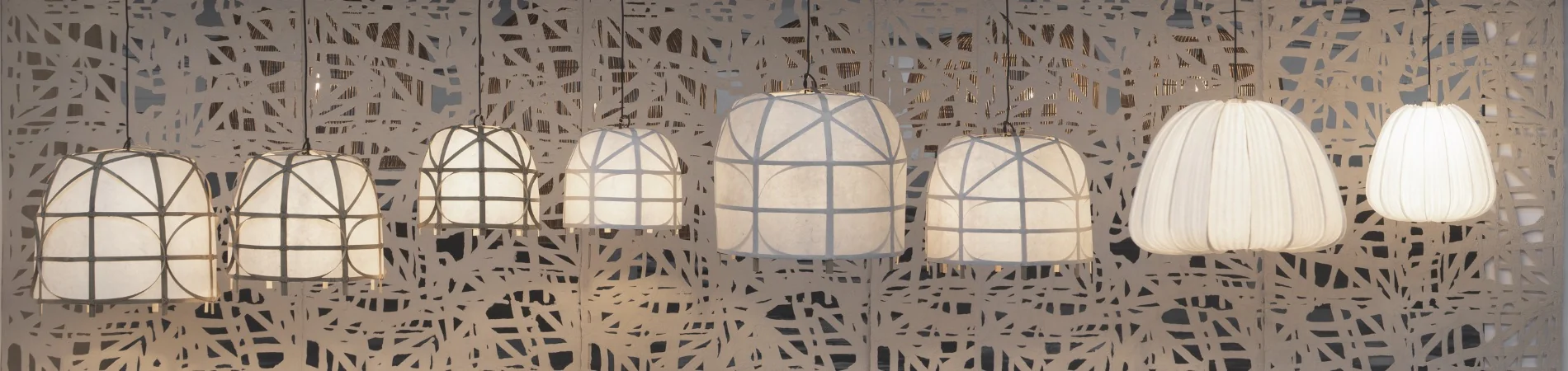 AYI Leuchten in verschiedenen Größen und Formen, mit weißen Stoffschirmen, vor einem abstrakten, grauen Hintergrund.