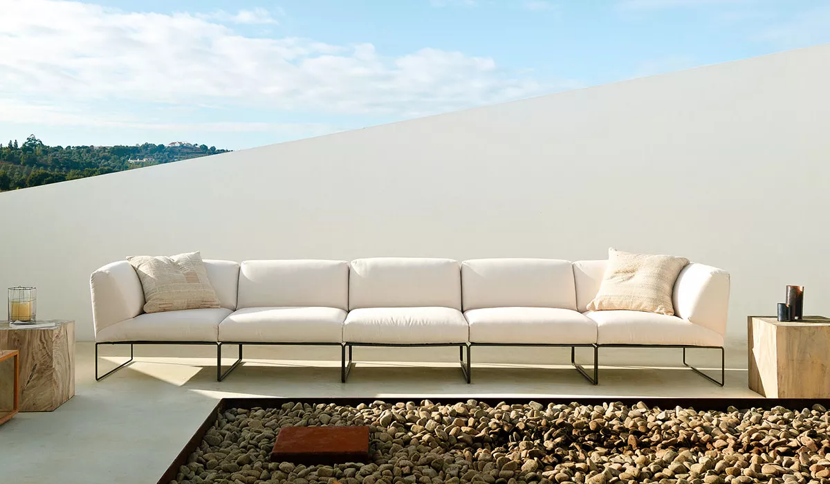 Andreu World Loungemöbel, weiß, auf einer Terrasse mit modernem Hintergrund und Steindekoration im Vordergrund.