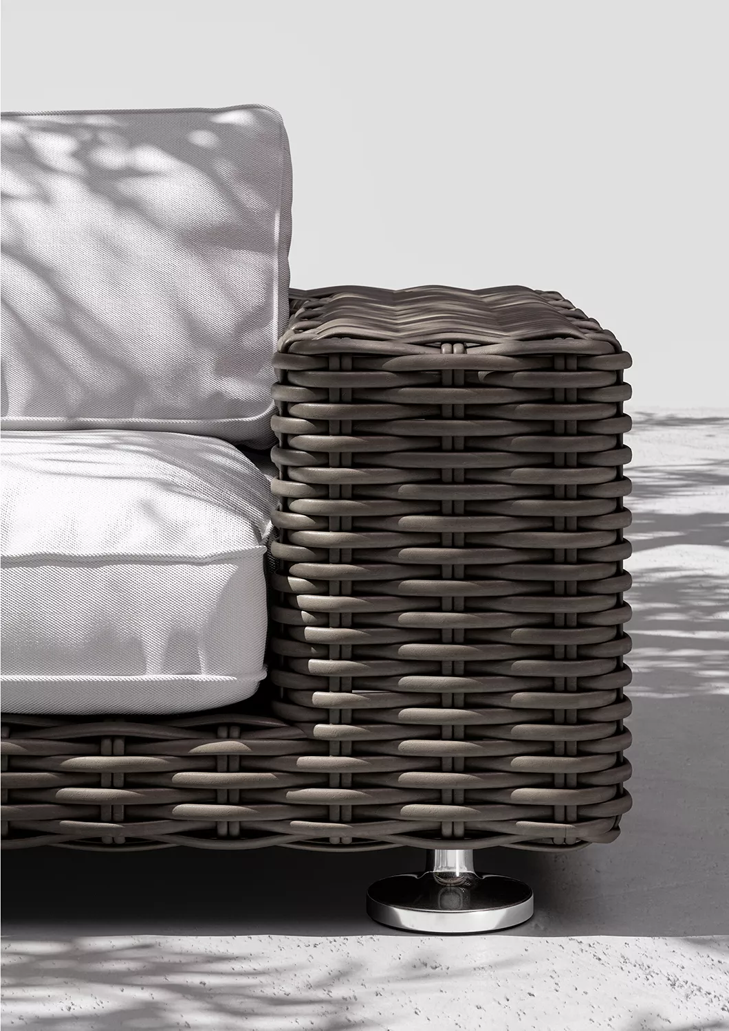 Dedon Paros Sofa in Nahaufnahme mit weißem Kissen und geflochtenem Design im Freien mit Schatten von Blättern auf dem Boden