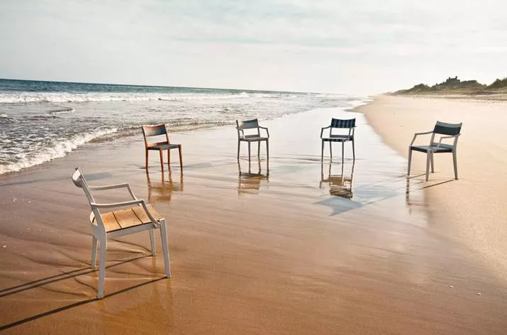 Dedon Play Essstuhl in verschiedenen Farben am Strand aufgestellt Moodbild mit fünf Stühlen im Sand und Meer im Hintergrund