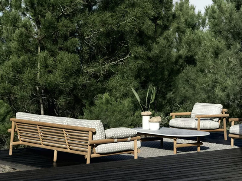 BeB Ayana Kollektion Sofa in Naturtönen auf einer Terrasse vor einem Hintergrund aus grünen Bäumen, mit passendem Tisch und Pflanzen.
