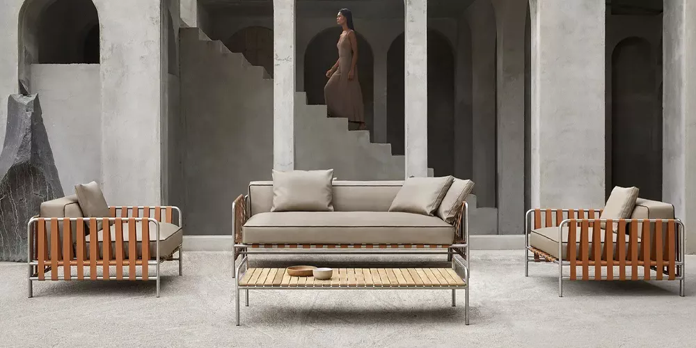 Gandia Blasco Onsen Lounge-Set in Beige und Braun vor einer Betonwand mit Treppe im Hintergrund, stimmungsvolle Szene.