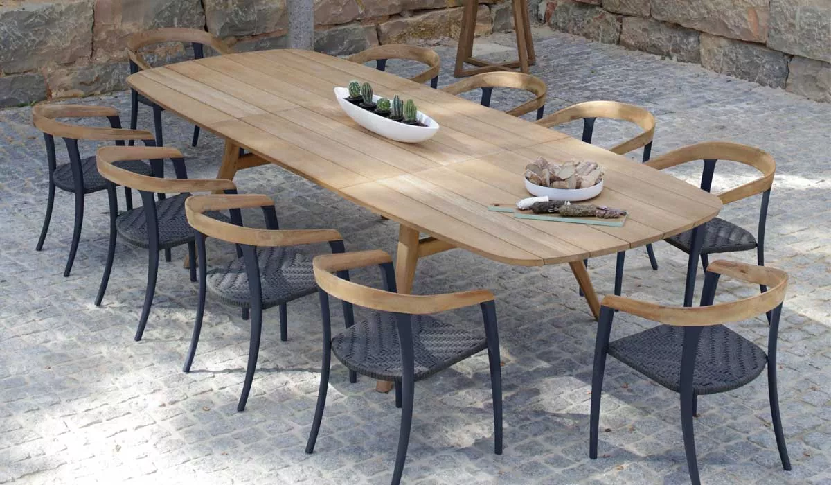 Royal Botania Zidiz Essgruppe in Holzoptik auf gepflastertem Hintergrund, bestehend aus einem langen Tisch und zehn Stühlen.