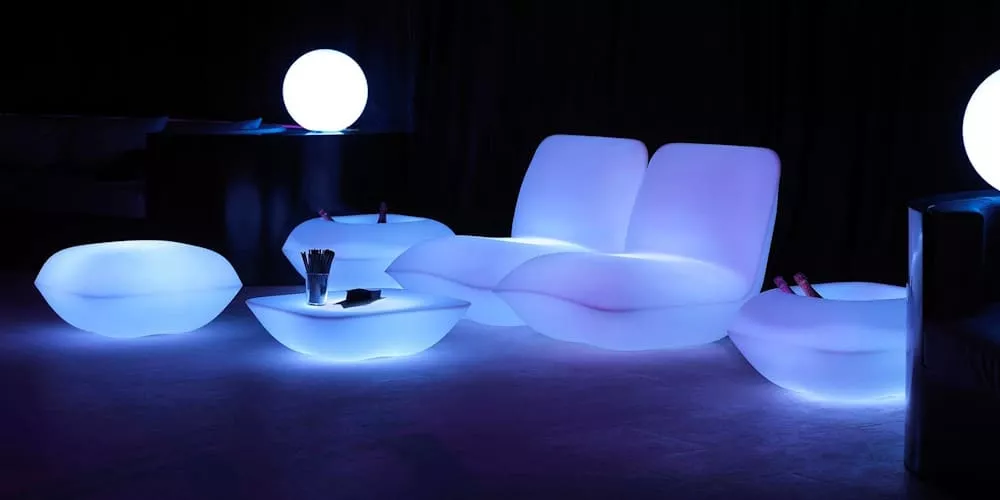 Beleuchtete Gartenmöbel von Villa Schmidt in Weiß, bestehend aus Sofa, Sesseln und Tischen, in stimmungsvoller Nachtaufnahme.