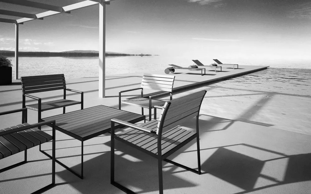 Schwarz-weiß Bild von R. Shults Garten-Lounge mit Sonnenliegen und Stühlen auf einer Terrasse am Wasser, entspannte Atmosphäre.