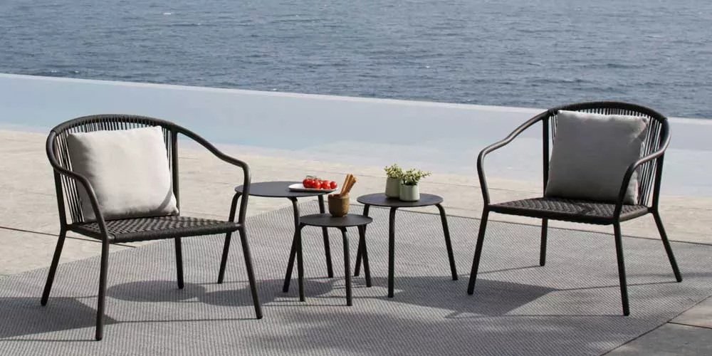 Royal Botania Samba Loungegruppe in Schwarz auf einer Terrasse mit Meerblick, bestehend aus zwei Sesseln und drei Beistelltischen.