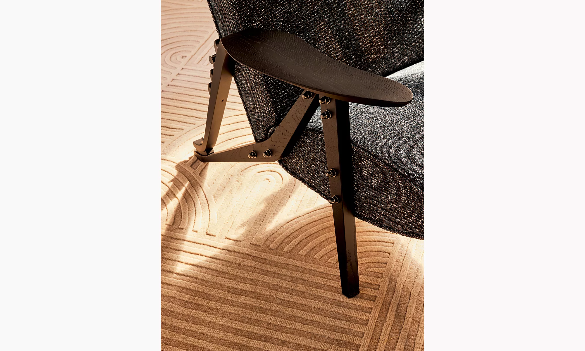 Der Zanotta 888 GildaCM Stuhl in Nahaufnahme zeigt die elegante schwarze Armlehne und das moderne Design auf einem strukturierten Teppich.