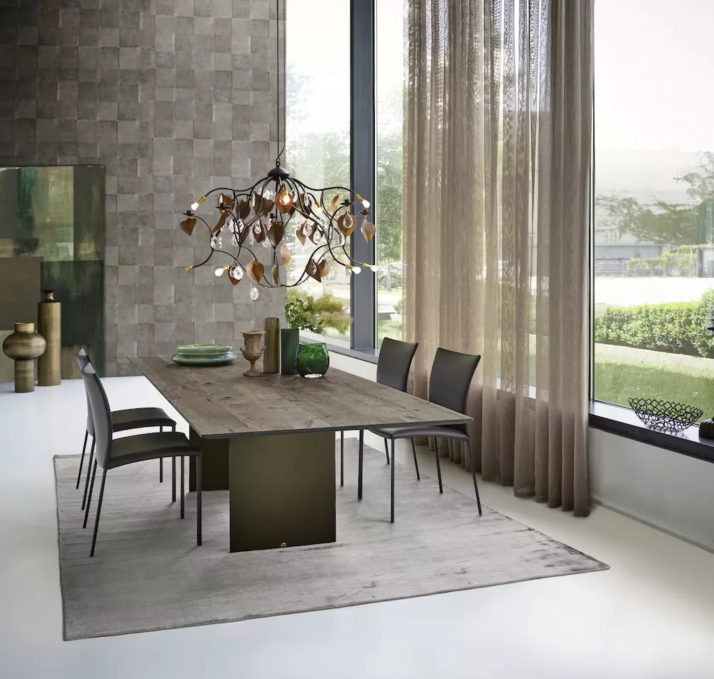 Essgruppe mit Draenert Atlas Tisch aus dunklem Naturholz und sechs schwarzen Stühlen in modernem Esszimmer mit großem Fenster und stilvoller Dekoration.
