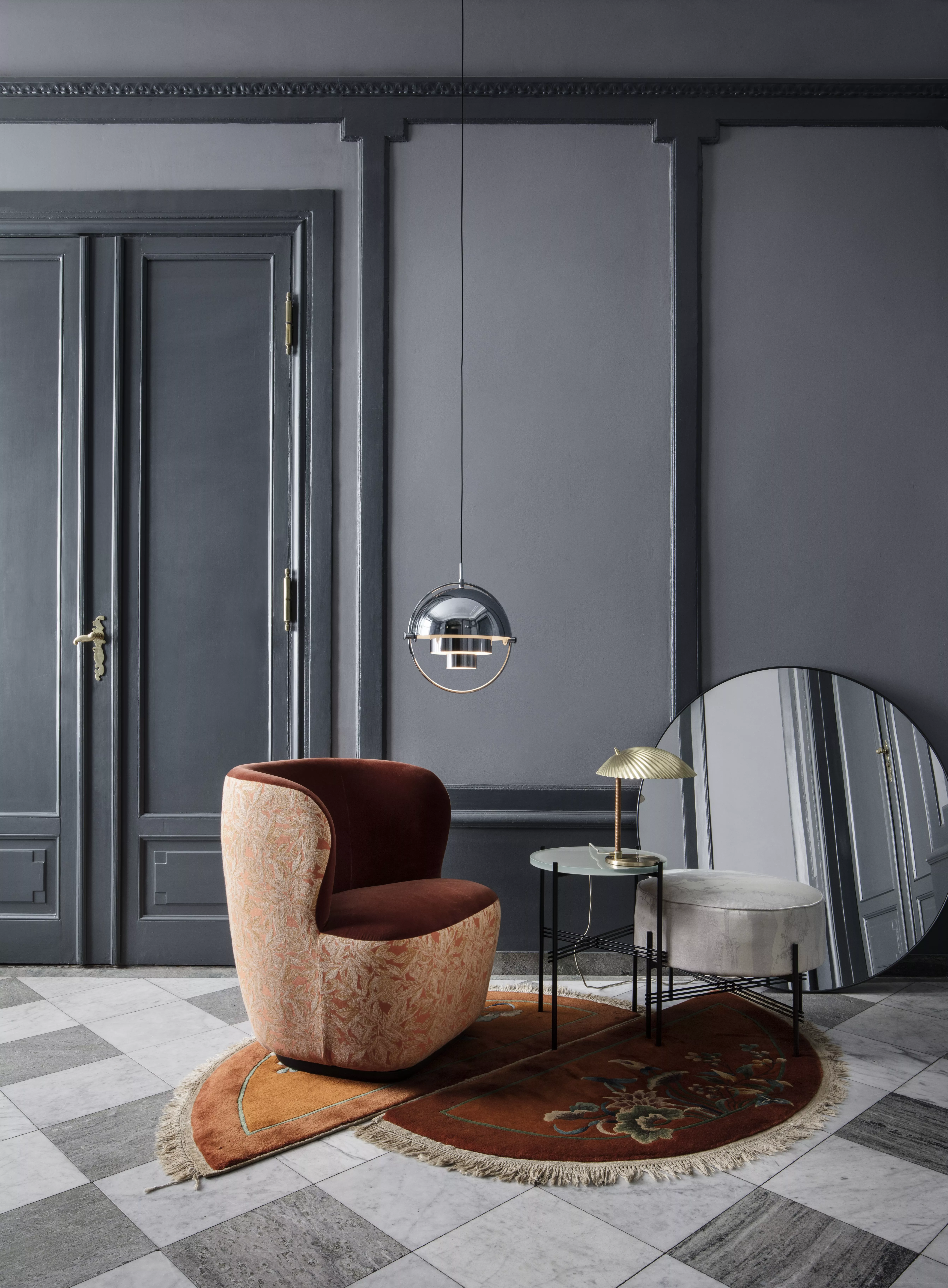 Ein stilvoll eingerichtetes Zimmer mit dem GUBI Multi-Lite Pendant einer Stay Lounge Chair einem TS Coffee Table einem TS Pouffe Round und einer 5321 Table Lamp.