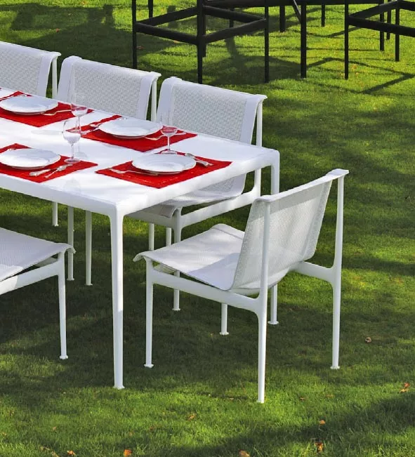 Knoll Studio 1966 Collection Essgruppe auf einer grünen Wiese gedeckt mit roten Platzsets und Weingläsern im Freien