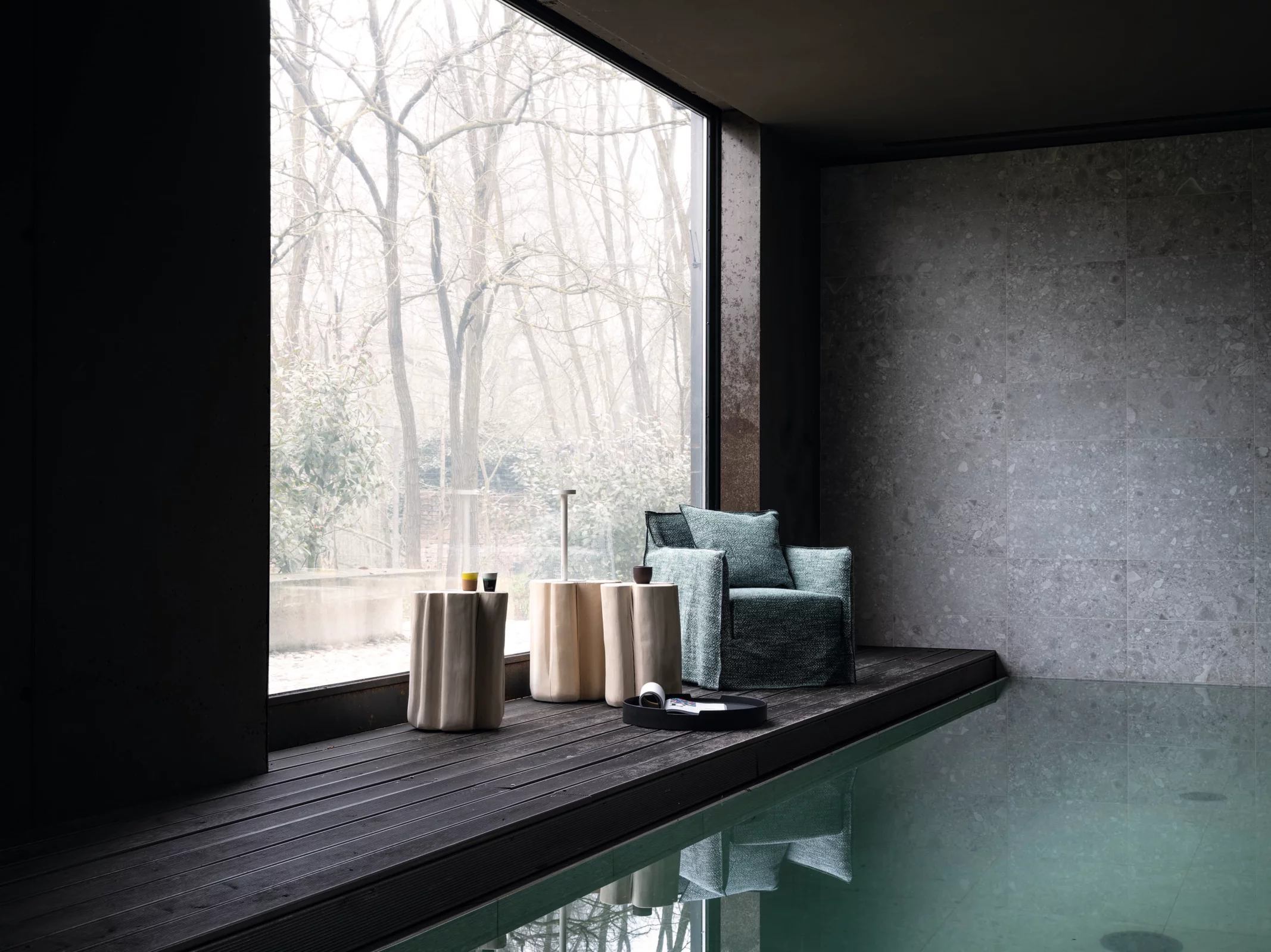 Gervasoni Beistelltische und Sessel in einem modernen Raum mit großen Fenstern und Blick auf einen winterlichen Wald