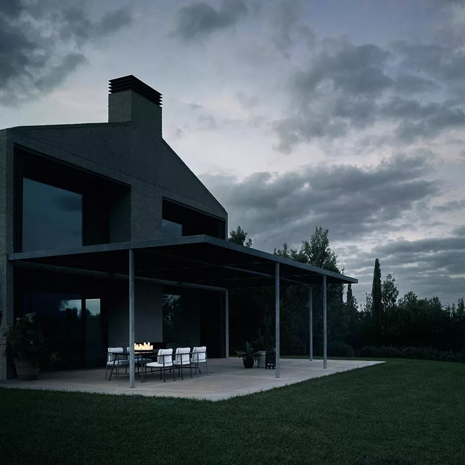 B&B Italia Borea Loungesofa und Outdoor Loungegruppe auf einer Terrasse bei Dämmerung mit einem modernen Haus im Hintergrund und bewölktem Himmel