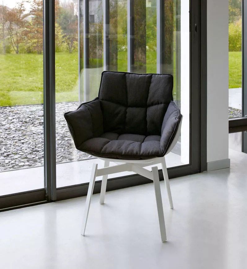 B&B Italia Husk Outdoor Armlehnstuhl in einem modernen Raum mit großen Fenstern und Blick auf einen grünen Garten
