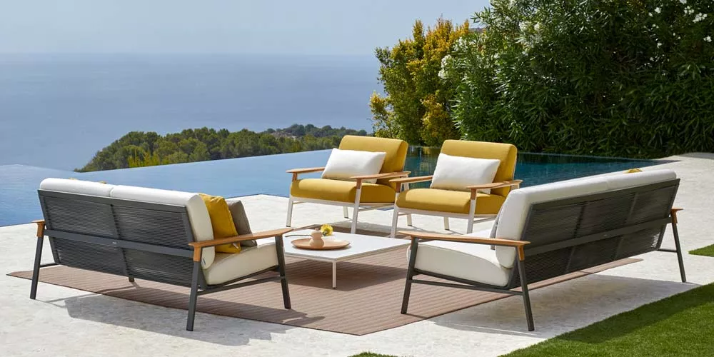 POINT Long City Outdoor Loungegruppe in Gelb und Weiß auf einer Terrasse mit Meerblick, bestehend aus Sofas und Sesseln um einen Tisch.